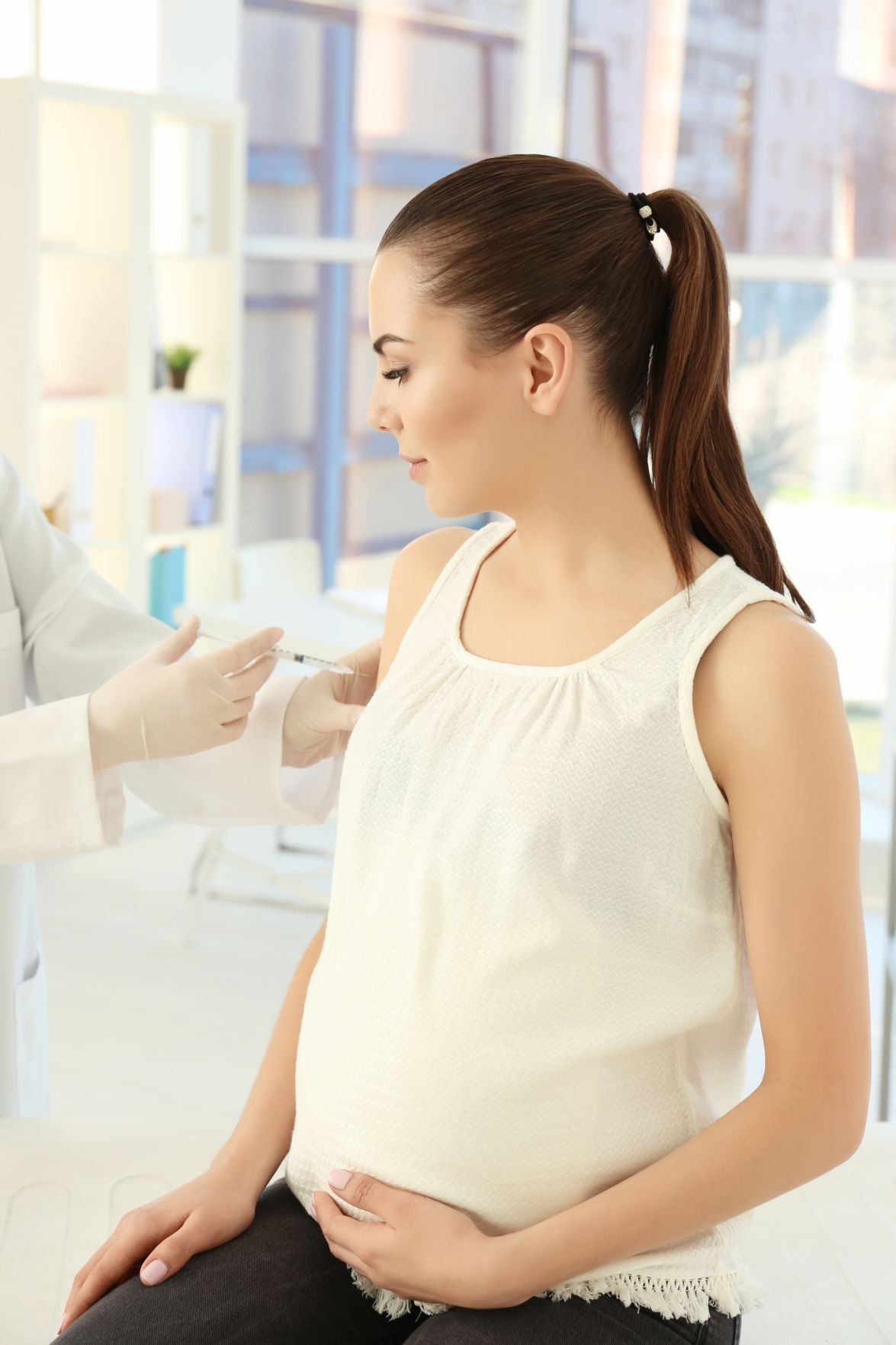 Young pregnant woman receiving vaccination in clinic